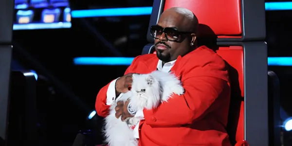   The Voiceの椅子に座って白い猫を抱えているCeeLo Green。