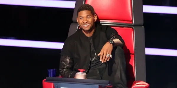  The Voice の椅子に座っているアッシャーは、腕をその上に垂らしてひざまずきます。