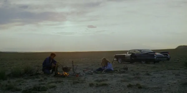   Badlands のオープン フィールドでたき火をしている 2 人のキャラクター。